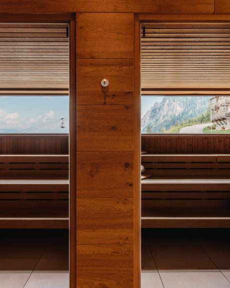 Zwei stilvolle Saunakabinen aus hellem Holz mit großzügigen Fenstern, die einen atemberaubenden Ausblick auf die umliegenden Kärntner Berge bieten. Die warme Atmosphäre und das alpenländische Flair sorgen für pure Entspannung im Almhotel Kärnten. Zwei der modernen Saunen mit Panoramablick im Almhotel Kärnten am Nassfeld