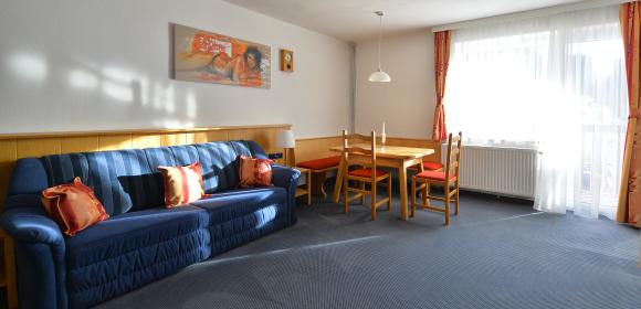 Familienzimmer "Standard" mit hellen Wohnbereich samt Tisch im Almhotel K&auml;rnten am Nassfeld