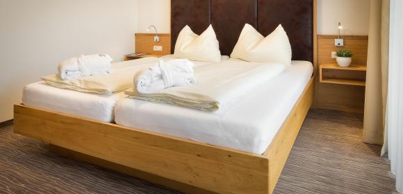 Komfortables Doppelzimmer mit Holzbett im Almhotel K&auml;rnten am Nassfeld