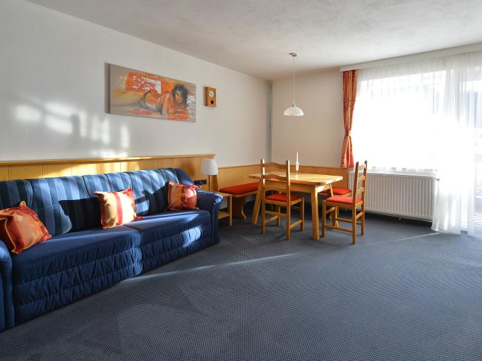 Familienzimmer "Standard" mit hellen Wohnbereich samt Tisch im Almhotel Kärnten am Nassfeld