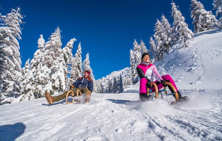 Rodelspaß im verschneiten Winterwald am Nassfeld in Kärnten in der Nähe des Almhotel Kärnten