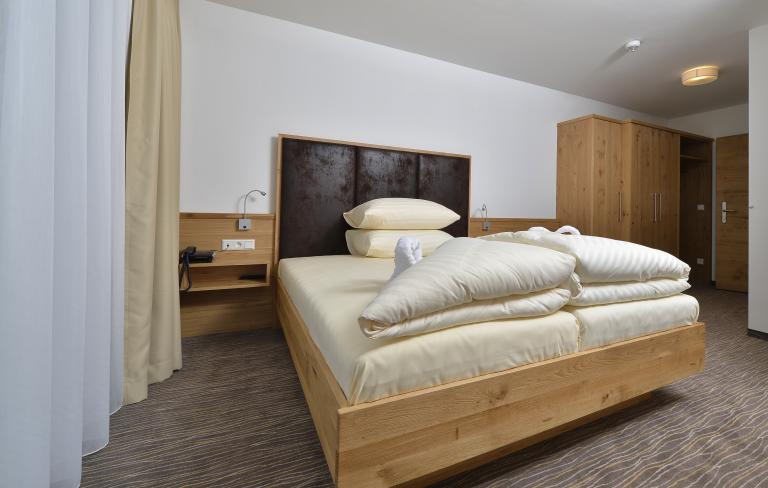 Komfortables Doppelzimmer mit Holzmöbeln im Almhotel Kärnten am Nassfeld