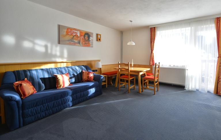 Familienzimmer "Standard" mit hellen Wohnbereich samt Tisch im Almhotel Kärnten am Nassfeld